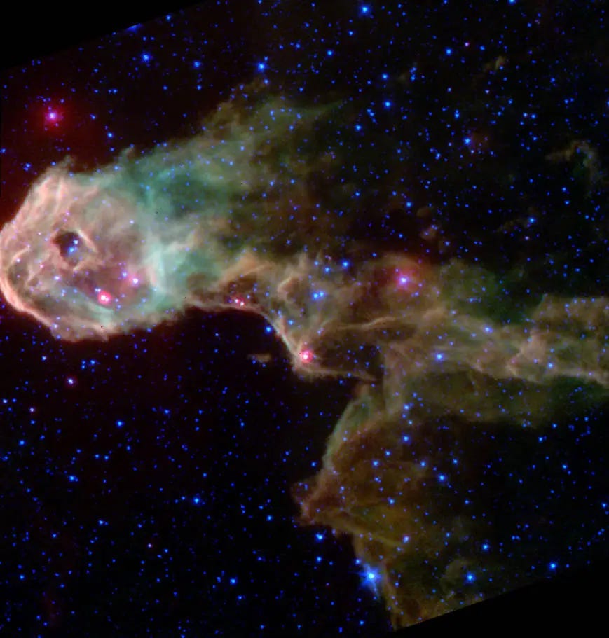 A gauzy flow of pink, green, and brown gases against the black background of space dotted with bright white-blue stars. 