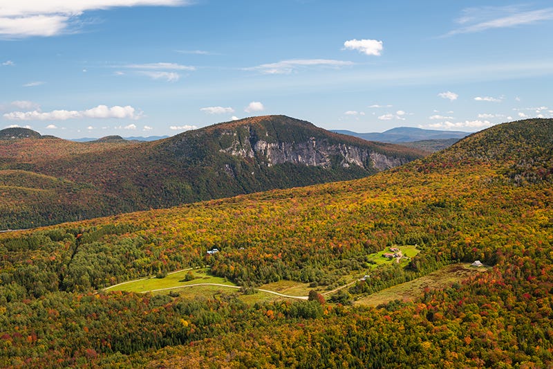 An aerial view of the trees changing color to red, orange, and yellow throughout Vermont’s mountains and valleys.