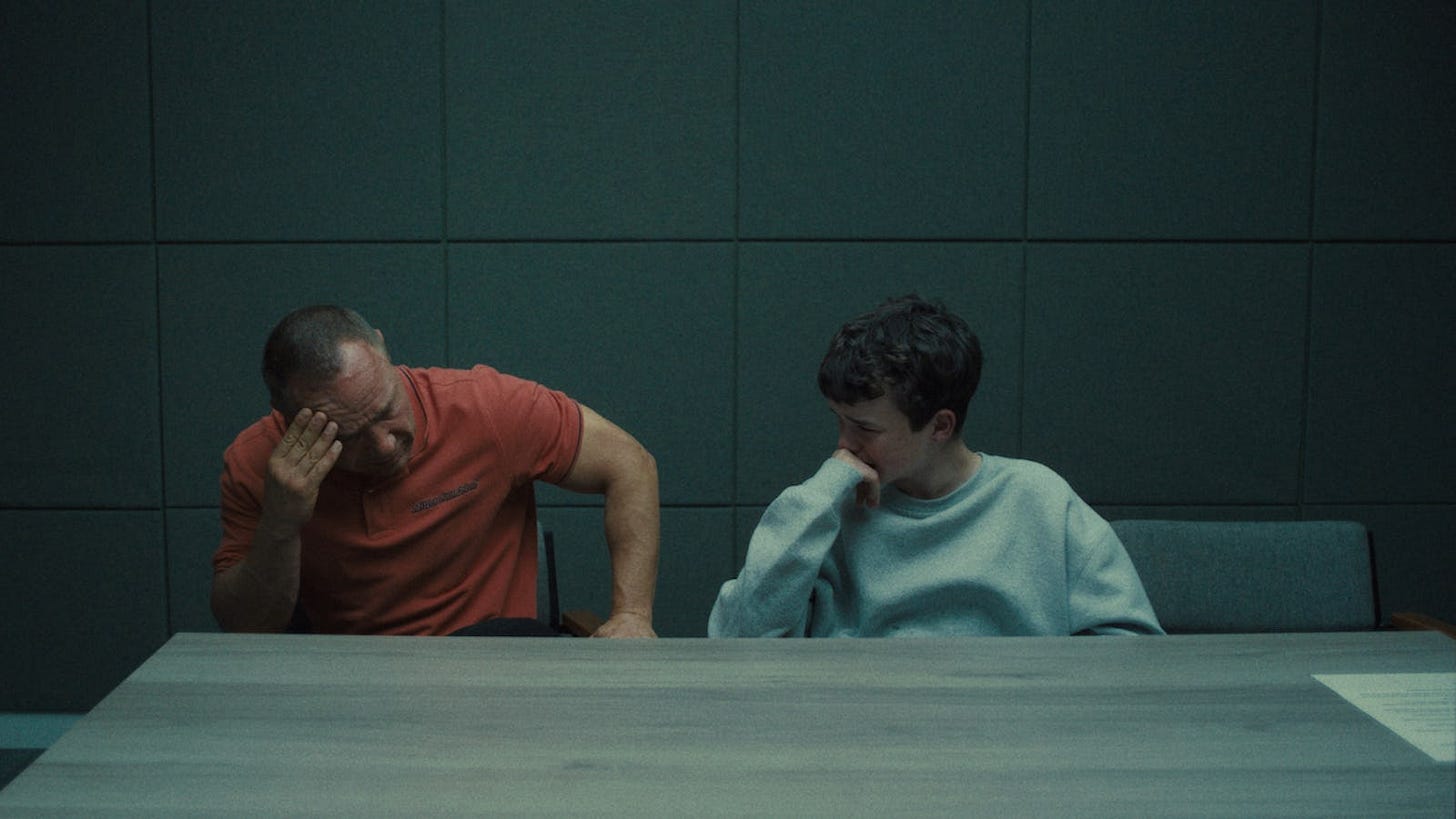 Adolescence på Netflix Jamie Miller stands next to his father, Eddie Miller, who dominates the room with his presence while Jamie looks on quietly in the background.