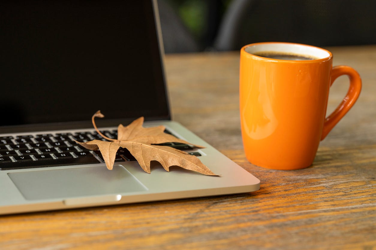 Autumn coffee cup beside a computer