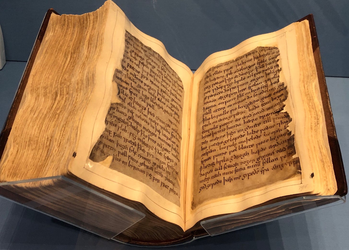 Two leaves of a medieval manuscript, mounted on modern paper, bound in a large volume, in a glass case.