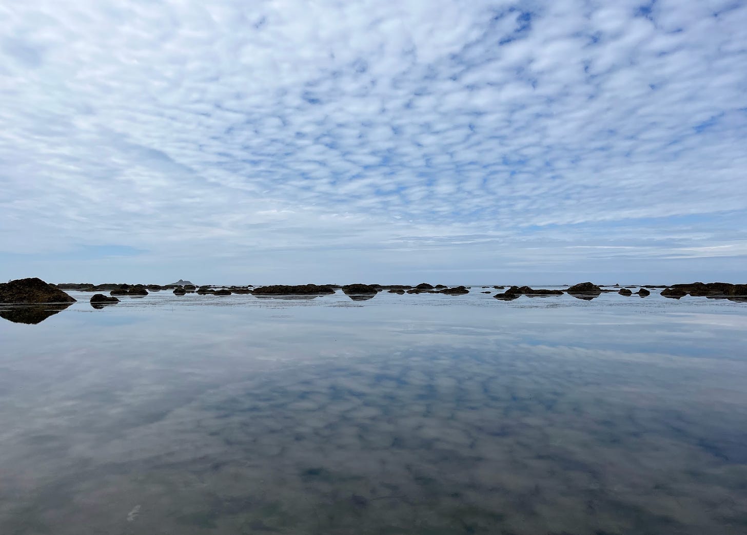 Party cloudy sky mirrored in tide pool.