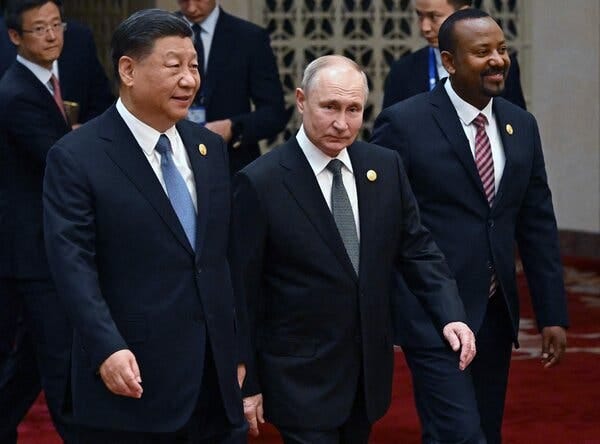 President Xi Jinping of China walks beside President Vladimir V. Putin of Russia as other people stand nearby.