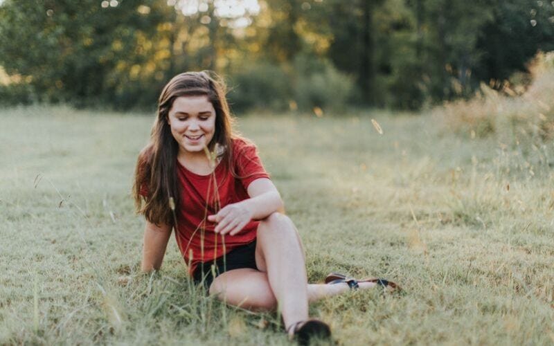 Teenage girl sitting in field.