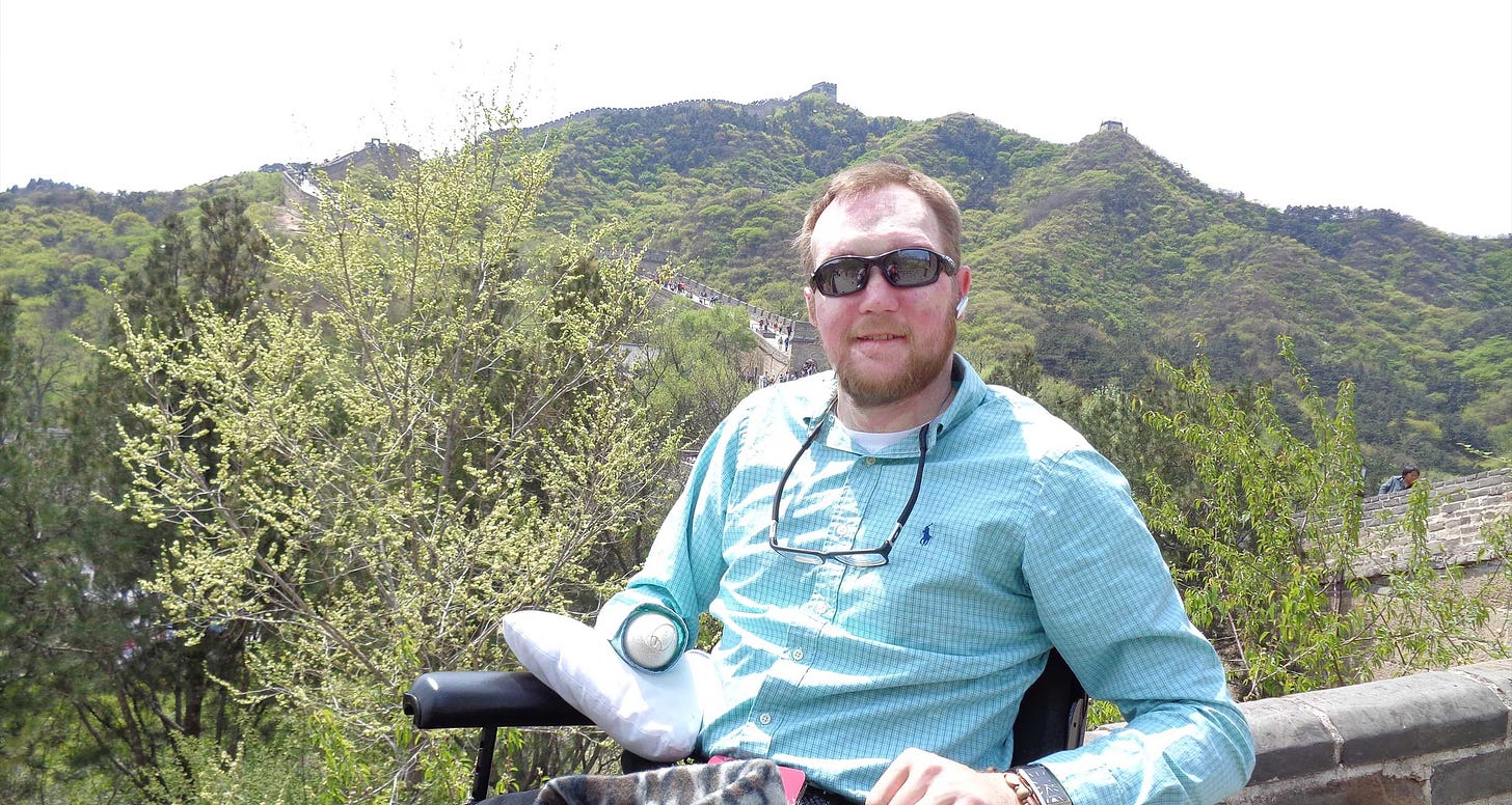 John seated in his wheelchair on top of the Great Wall of China.