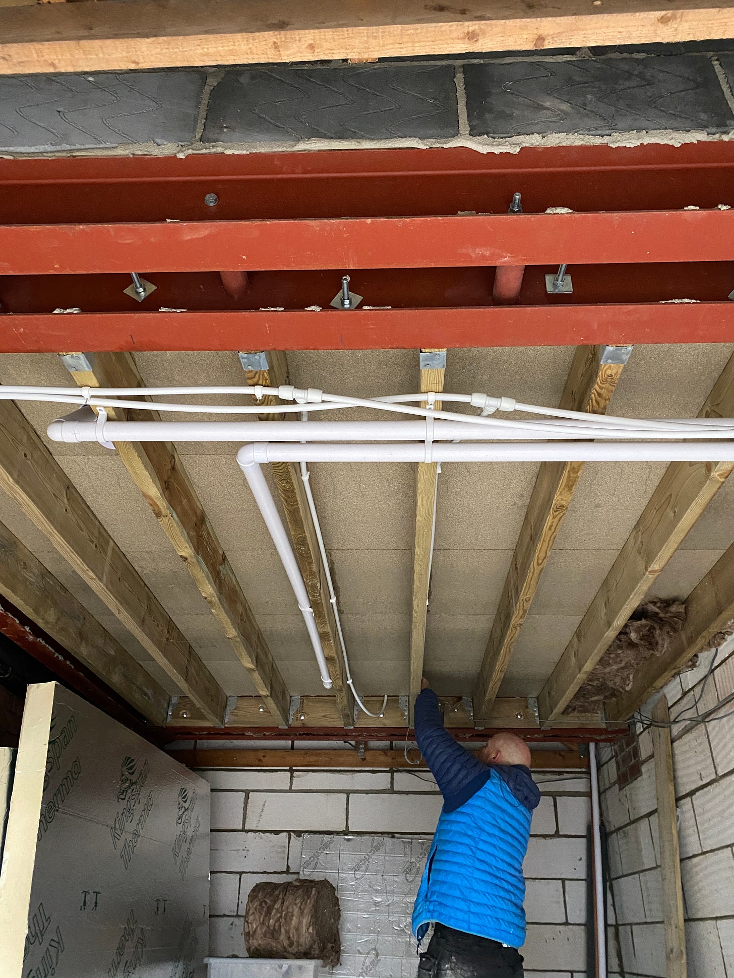 garage ceiling with wooden rafters and drainage pipework on show