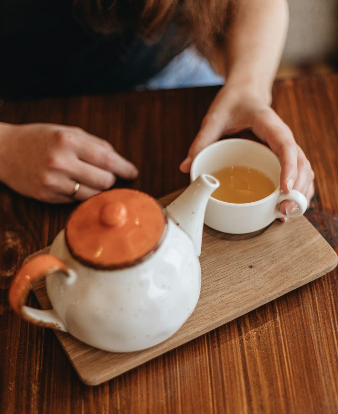 person pouring white liquid on white ceramic teapot