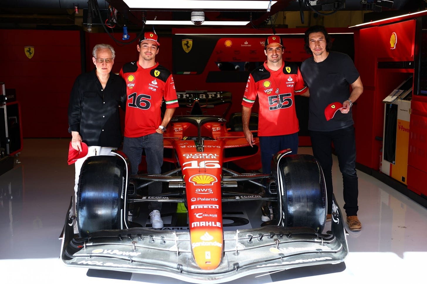 Michael Mann and Adam Driver posing with Ferrari drivers Charles Leclerc and Carlos Sainz with the Ferrari F1 car