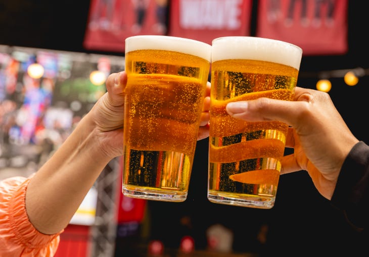 Two people clinking pints of beer together