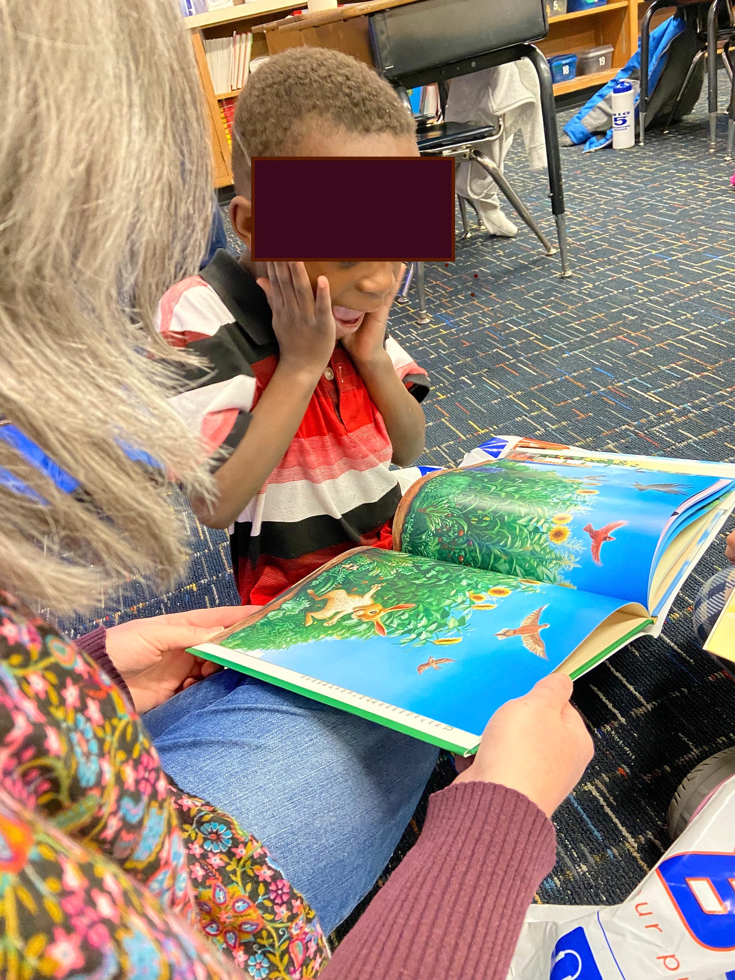 Boy expresses surprise when he turns the page of a picture book on an abundant, blooming garden