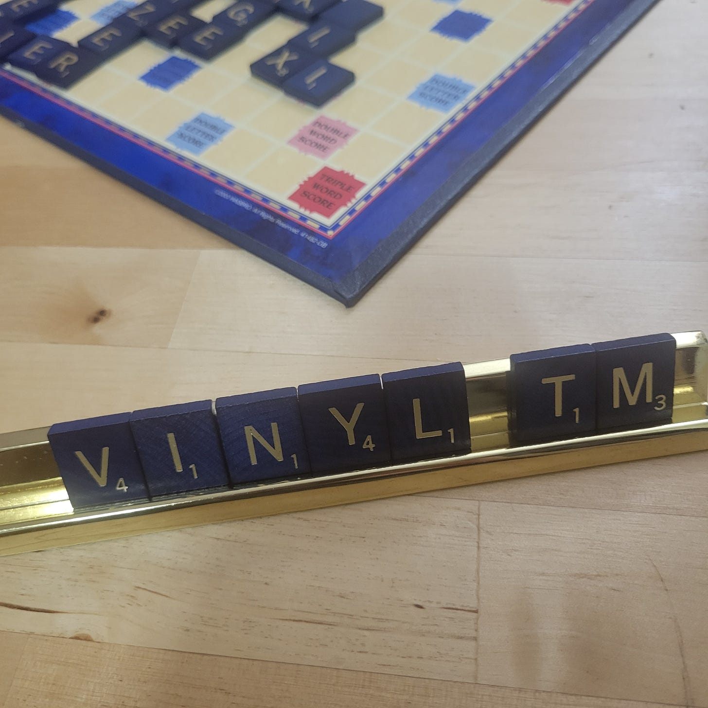 Scrabble board game. Gold rack has letters: "V I N Y L // TM