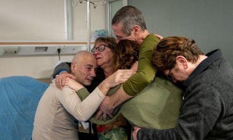 Louis Har and Fernando Simon Marman are hugged by three members of their family in a hospital room