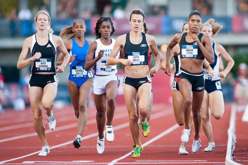 Five runners run in lanes one and two during a track race at Hayward Field. A young Chanelle Price, wearing a white uniform, is in the center.