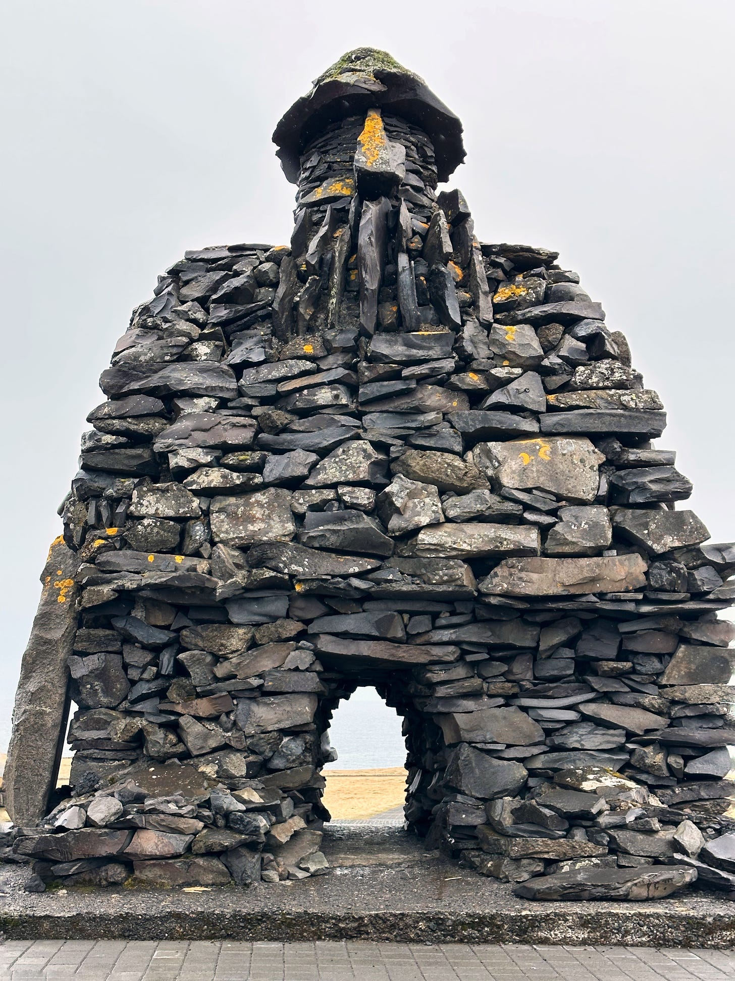 Full size image of the stone troll Bárður Snæfellsás.  For scale one adult man can stand comfortably in the opening between the ground and his knees.  The troll has a stone beard and hat.