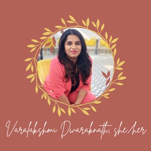 A woman wearing a coral suit sits and smiles with her name, Varalakshmi Dwaraknath, and pronouns, she/her, underneath in cursive font.