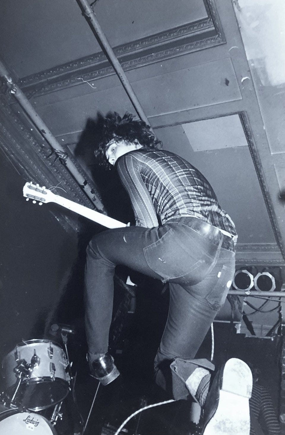 Rex John Shelverton jumping off a drum kit with his guitar