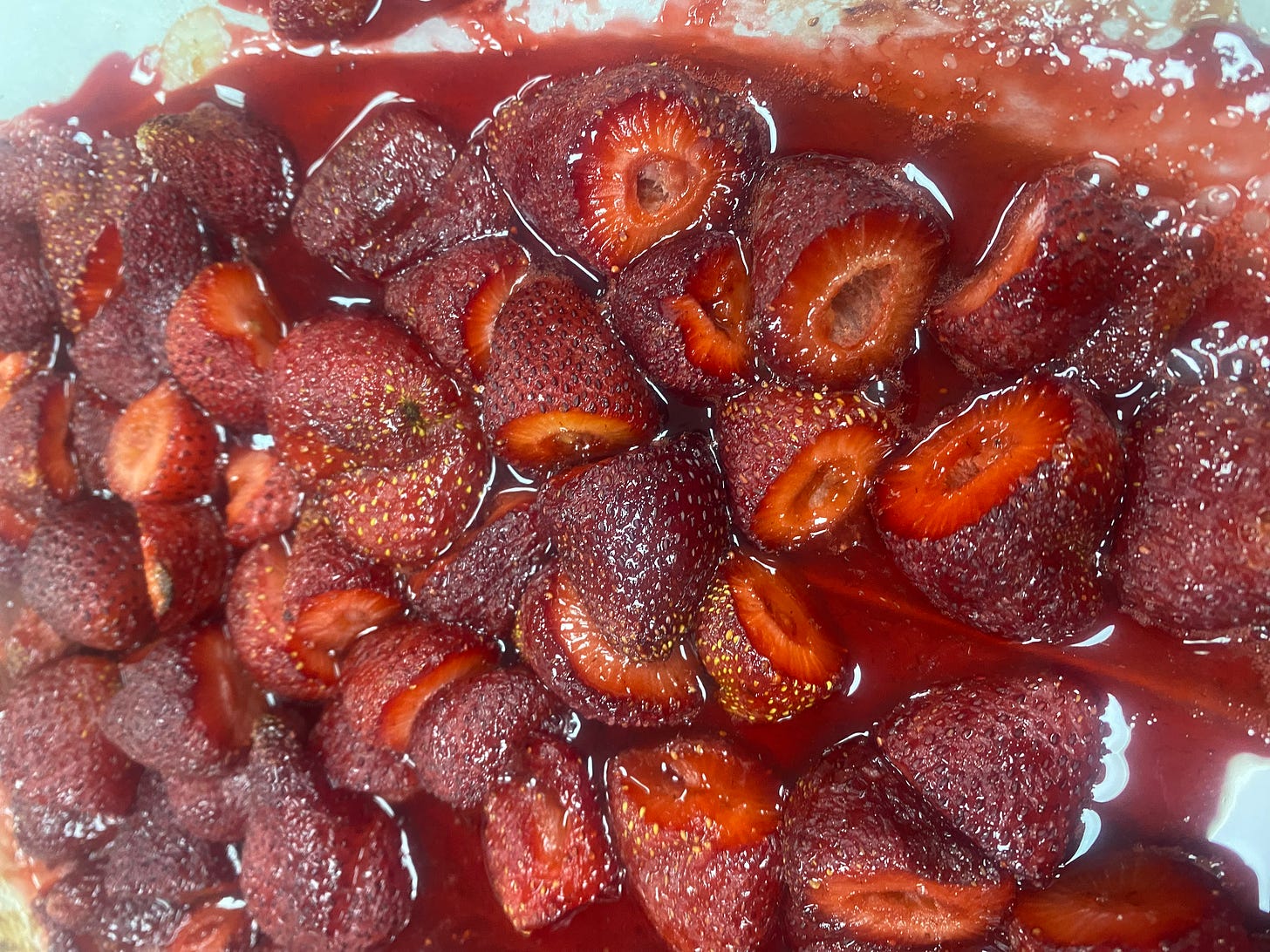 a pan of roasted strawberries. The berries are caramelized and in a dark red syrup. 