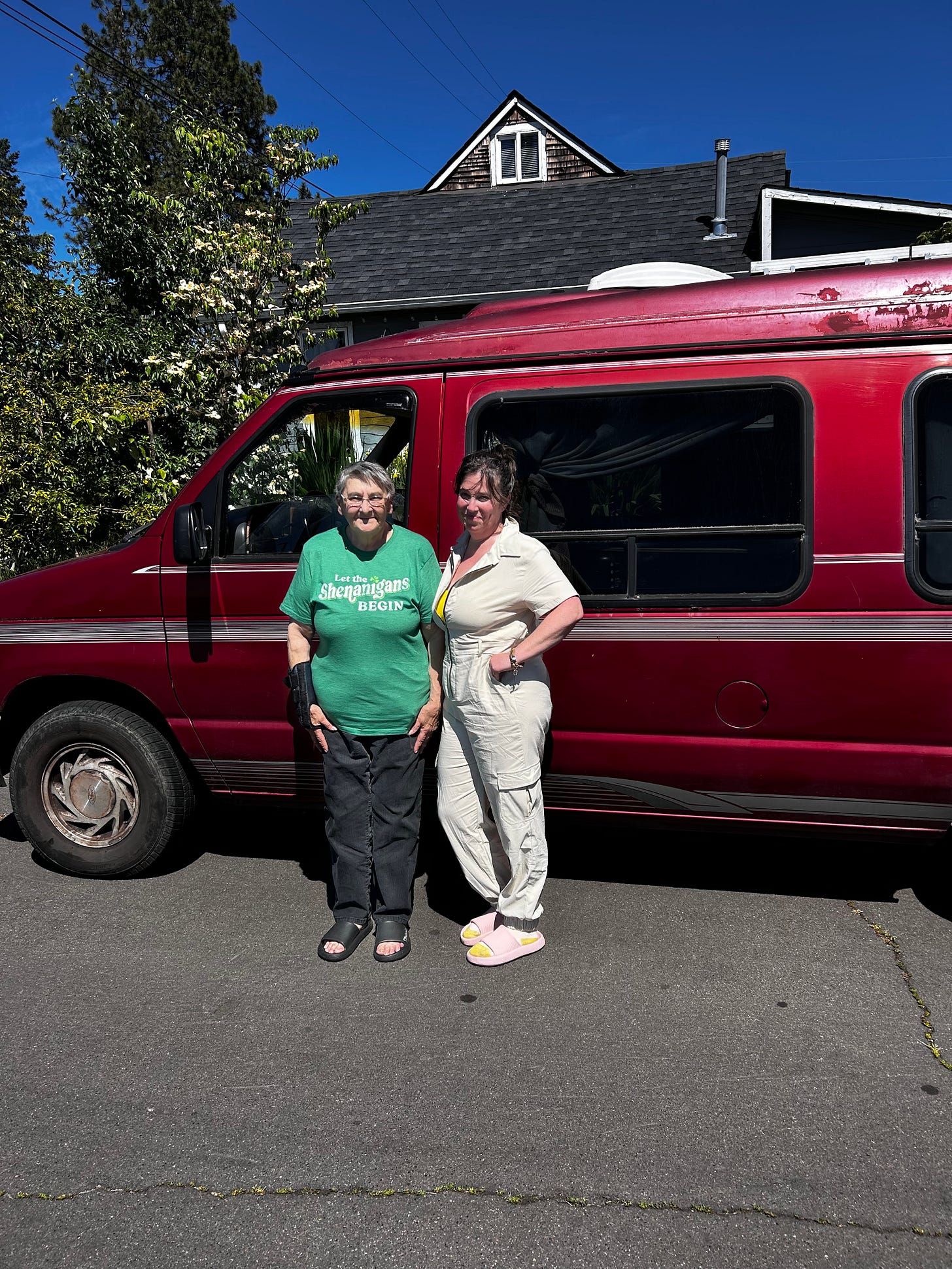 Two women in front of a ruby red van, the van's new person, Witchy Mama, and her old person, author Holly Starley Two women in front of a ruby red van, the van's new person, Witchy Mama, and her old person, author Holly Starley