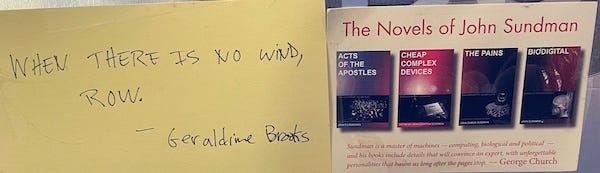 Photo of 2 cards taped to a wall. On the left, in sloppy handwriting: "When there is no wind, row." — Geraldine Brooks. On the right, a postcard with the heading "The novels of John Sundman" and images of 4 book covers. 