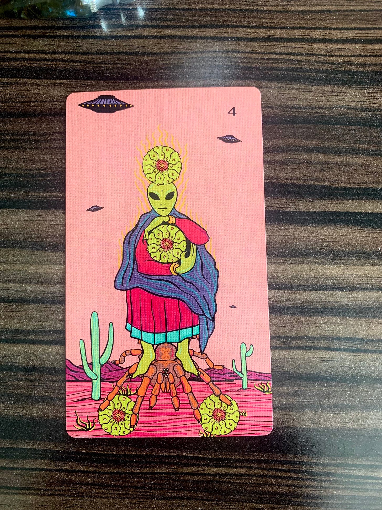 A tarot card. The four of cacti. An alien stands on the back of a spider with two cacti at its feet, another at its heart, and a fourth at its head.
