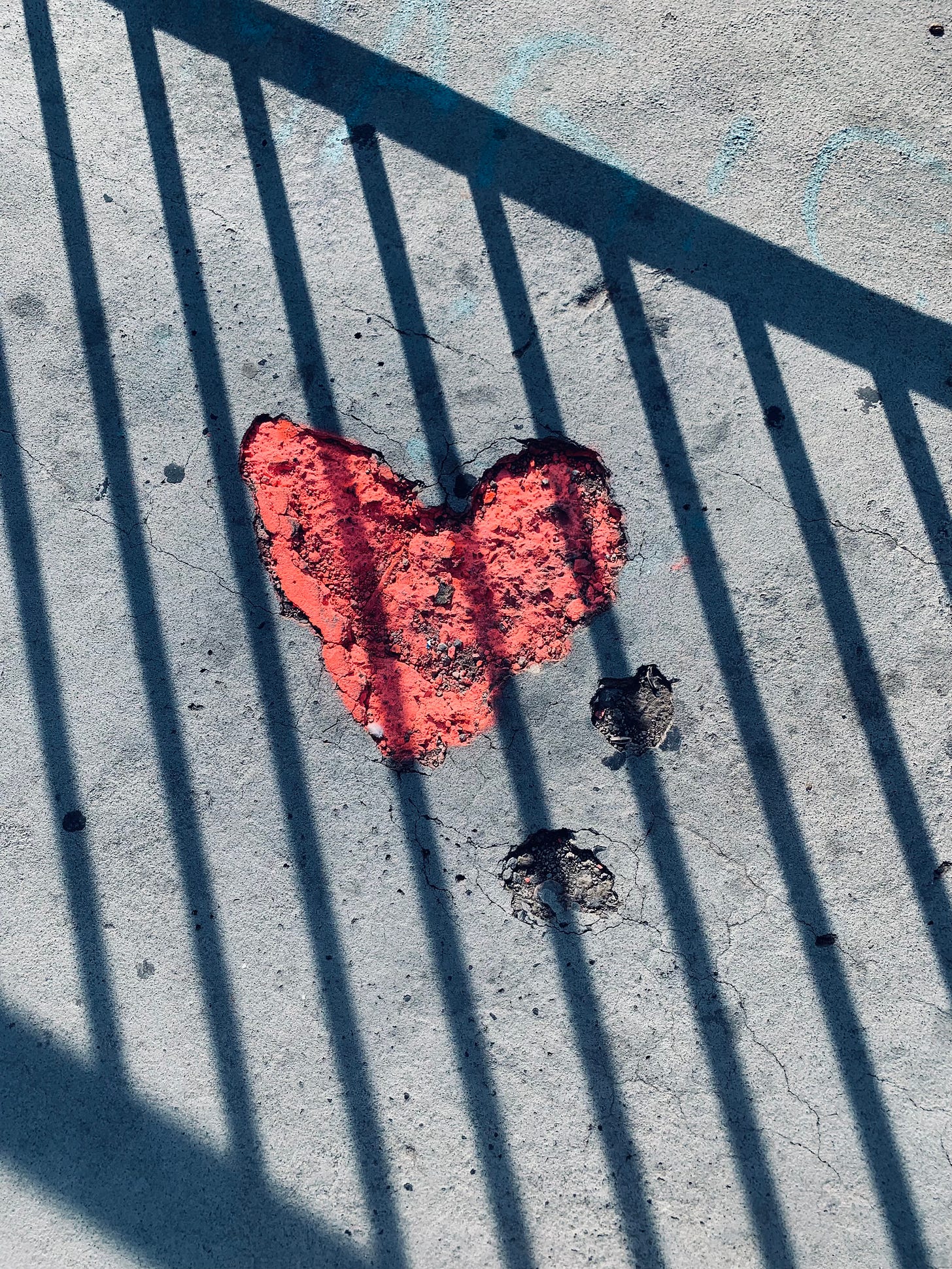 Someone has spray painted a heart-shaped divot in the cement a bright shade of red.