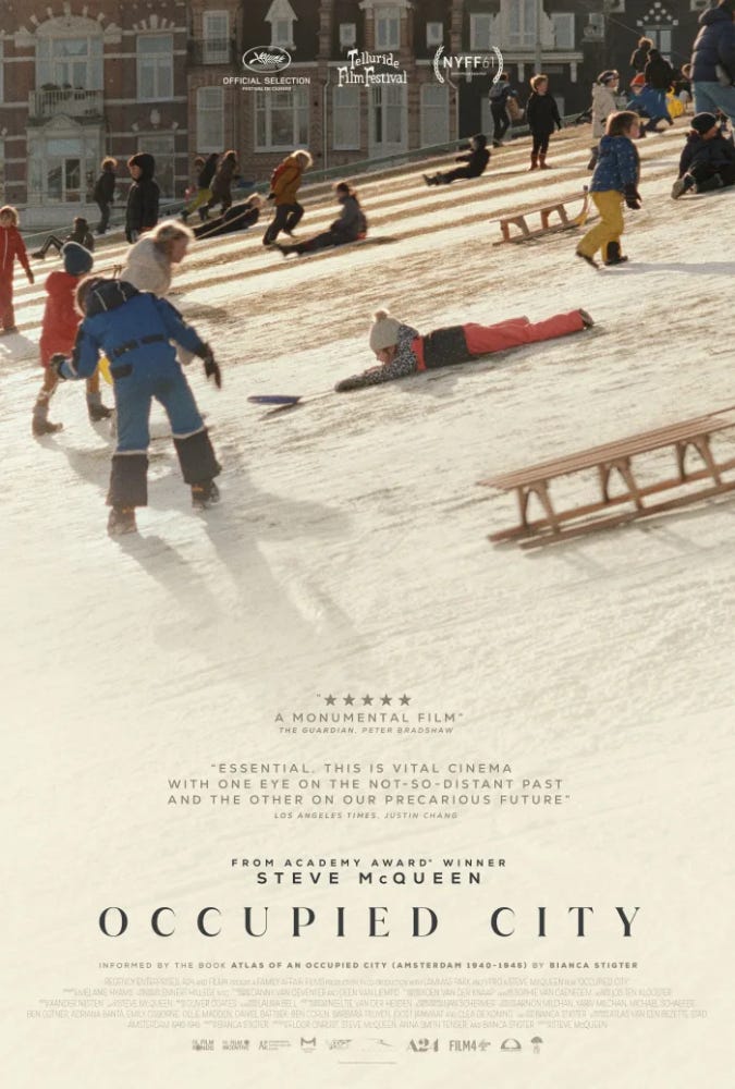 Movie poster for Occupied City, showing the film still of a snowy slope with many wooden sleds and children in snow suits. Text includes excerpts of two film reviews: “A monumental film” -The Guardian, Peter Bradshaw and “Essential. This is vital cinema with one eye on the not-so distant past and the other on our precarious future.” - Los Angeles Time, Justin Chang