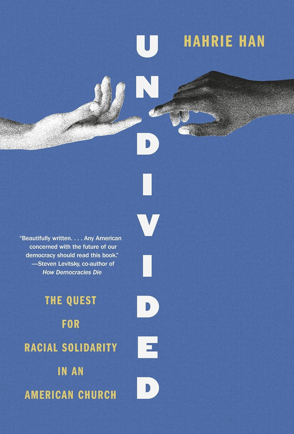 The book cover for “Undivided,” which is royal blue with teh image of a black hand and a white hand reaching to touch index fingers.