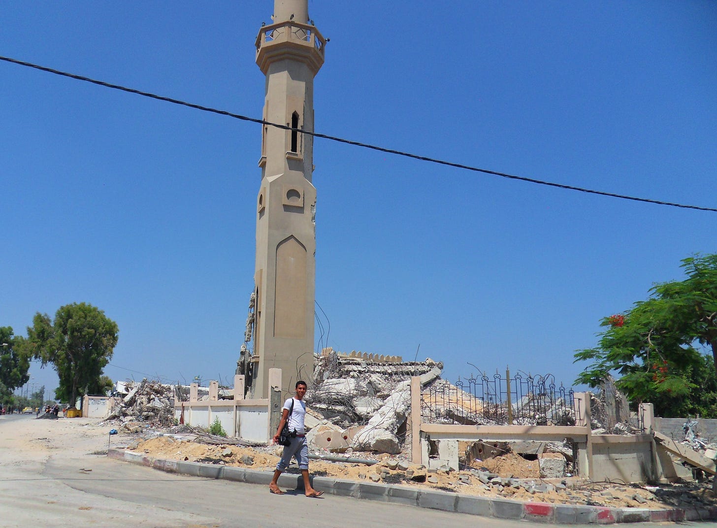 A man walks past the rubble of a mosque, where only the minaret still stands