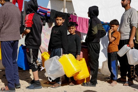 Boys hold containers while they line up in a displacement camp in Gaza