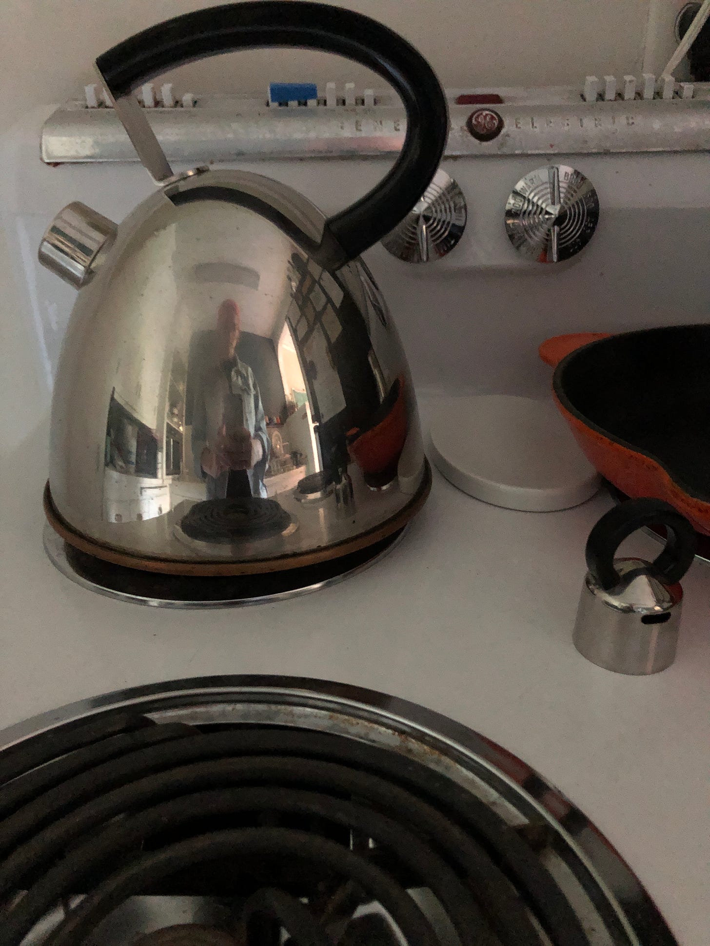 a stove with my reflection in a tea kettle