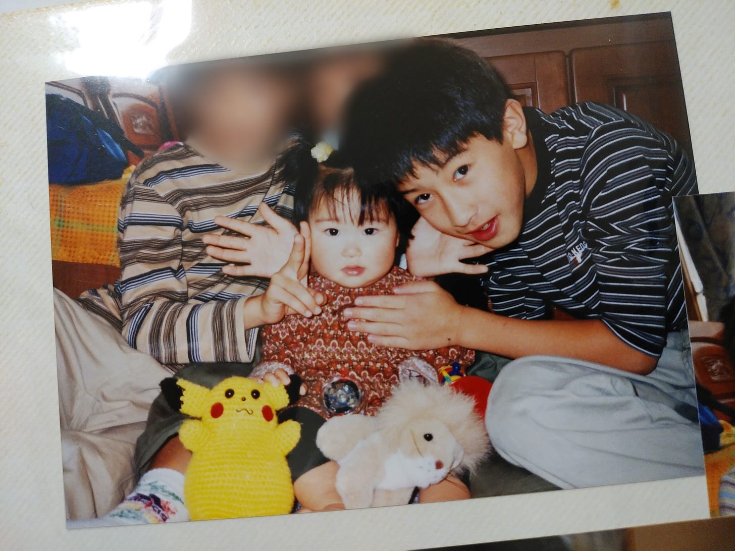 A photograph of Tsukasa (pictured right) along with his sister, with a knitted Pikachu made by his grandmother