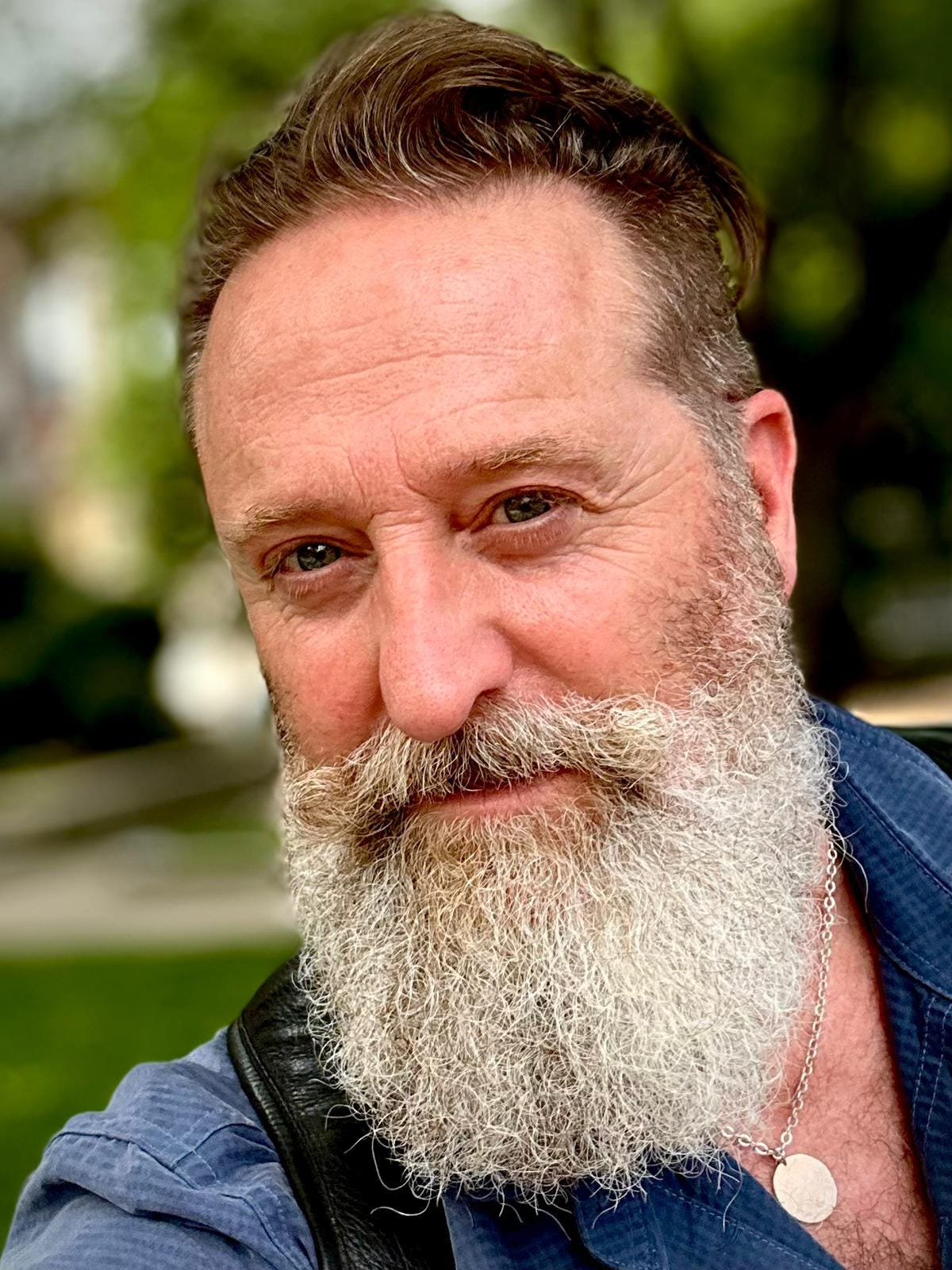 Color photo of a handsome older man with a full white beard and blue eyes.