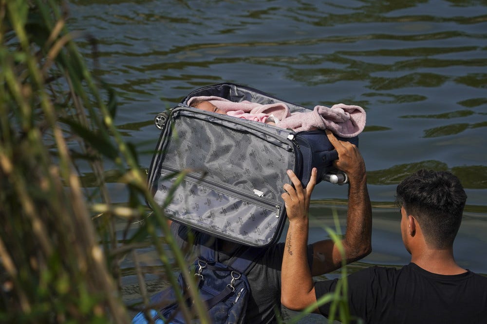 An illegal immigrant crosses the Rio Grande river with a baby in a suitcase