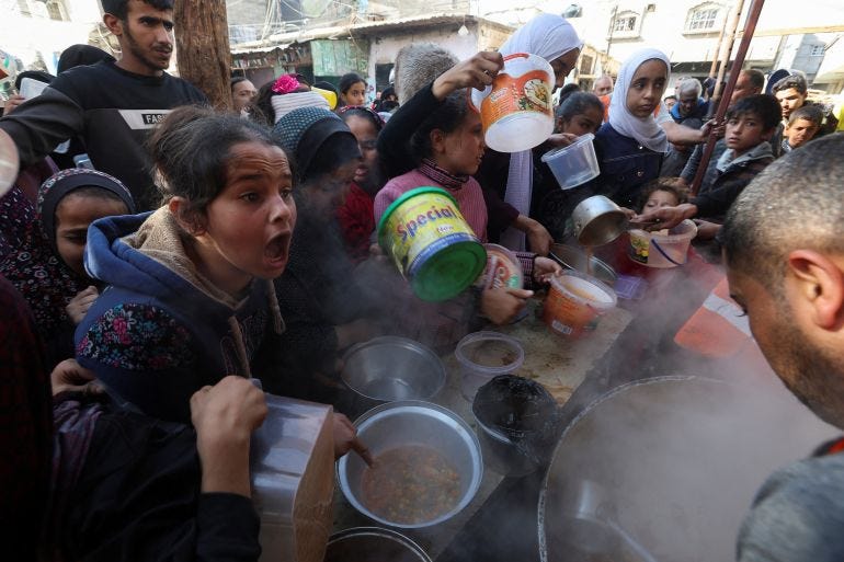 people hold pots out to get from from a stove in a crowd