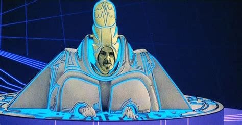 Man from Tron in a wide triangle suit and a long funny hat, sitting at a computer