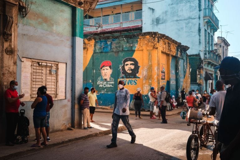 Customers wait in line to enter a grocery store in Havana, Cuba near portraits of the late revolutionary Ernesto ‘Che’ Guevara and the late Venezuelan President Hugo Chavez