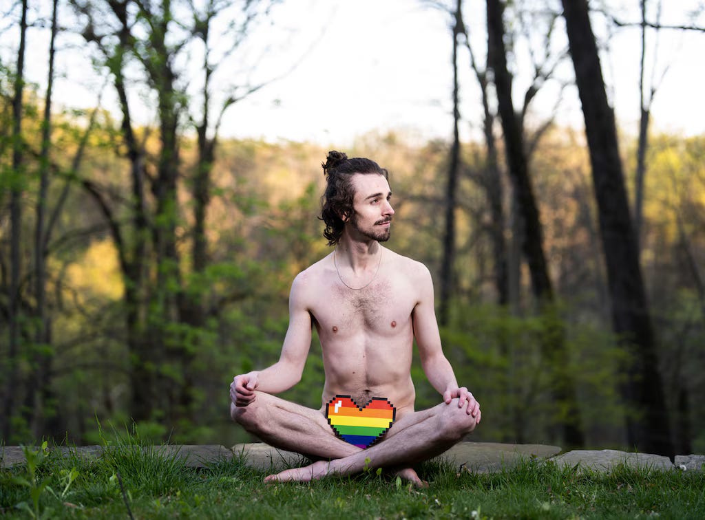 The artist, Tavish Forsyth, sits nude in a natural setting with a printed rainbow heart emoji covering their genitals. 