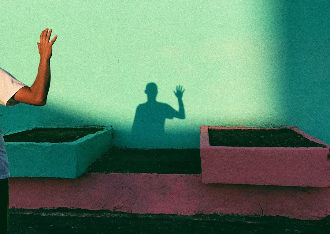 person waving reflecting shadow on teal paint