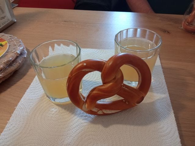 Homemade apple juice and a pretzel.