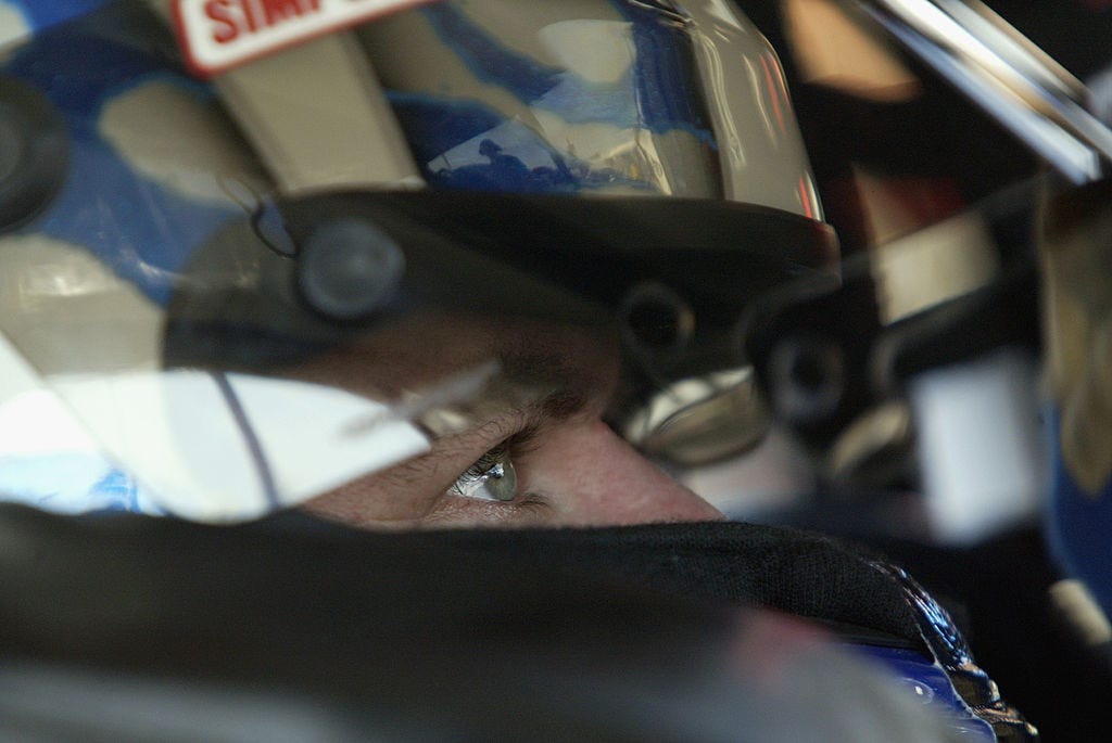 Jerry Nadeau sits in a race car, wearing a helmet.