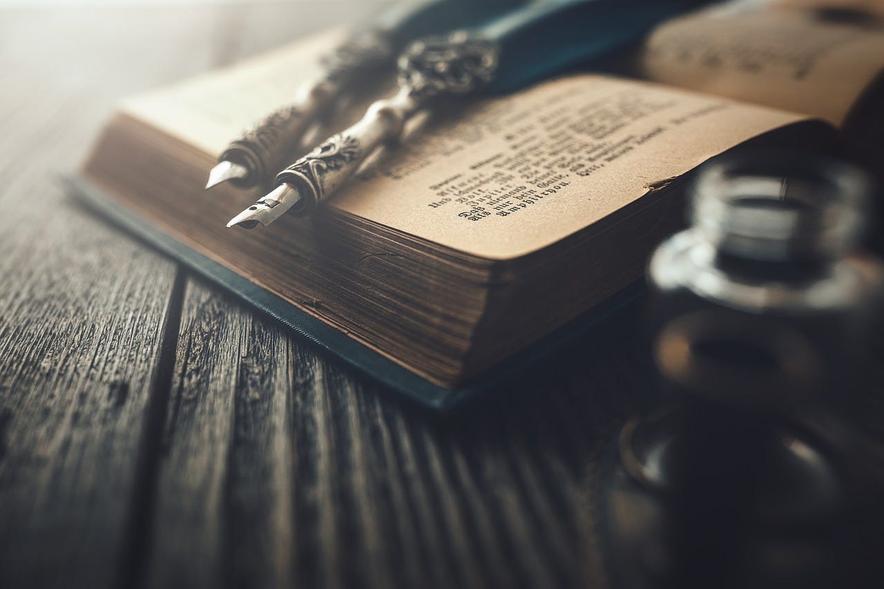 Photograph of fountain pens on an old book, on a wooden table