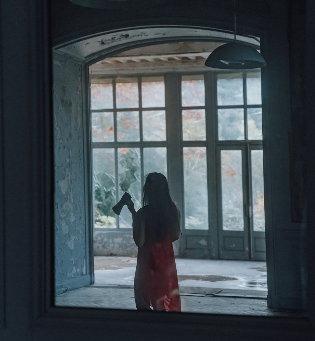 woman in red dress standing in front of window