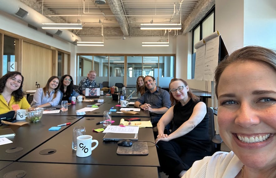 8 members of CPLA gathered around a large table smiling.