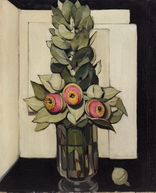 Margaret Preston’s painting Western Australian gum blossom. A vase containing green-white eucalyptus leaves makes a column at the center of the painting. The leaves are strongly lit and shadowed. Near the bottom of the arrangement are three round gum blossoms in bright pink and yellow. Behind the vase are cream colored panels. A single green bud is placed next to the vase on a dark, reflective surface. The feeling is one of great intensity.