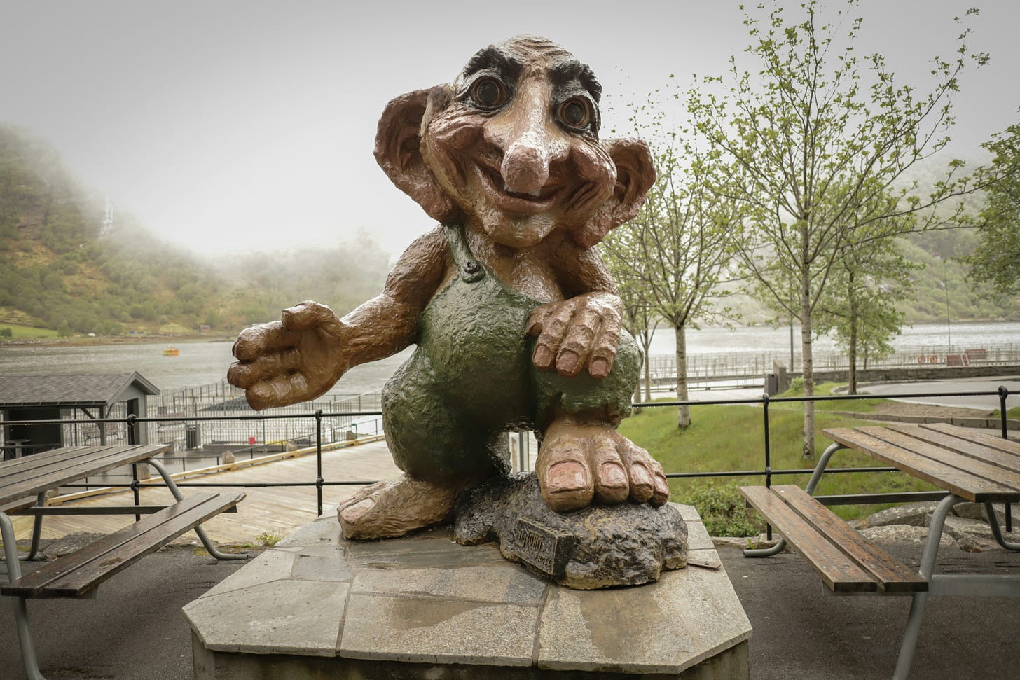 A statue of a troll sits in a park.