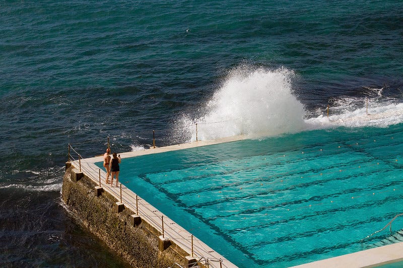 Two women stand next to Bondi's ocean pool in Sydney.