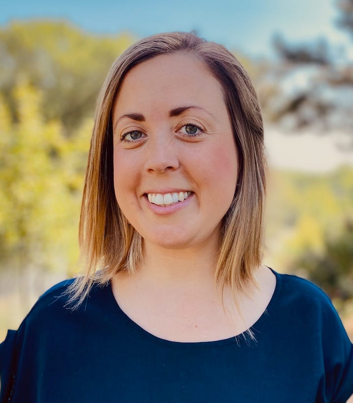 Headshot photo of Sawyer. She has shoulder length dirty blond hair, pink and white skin, and a blue blouse. She is smiling and there are trees in the background on a sunny day.