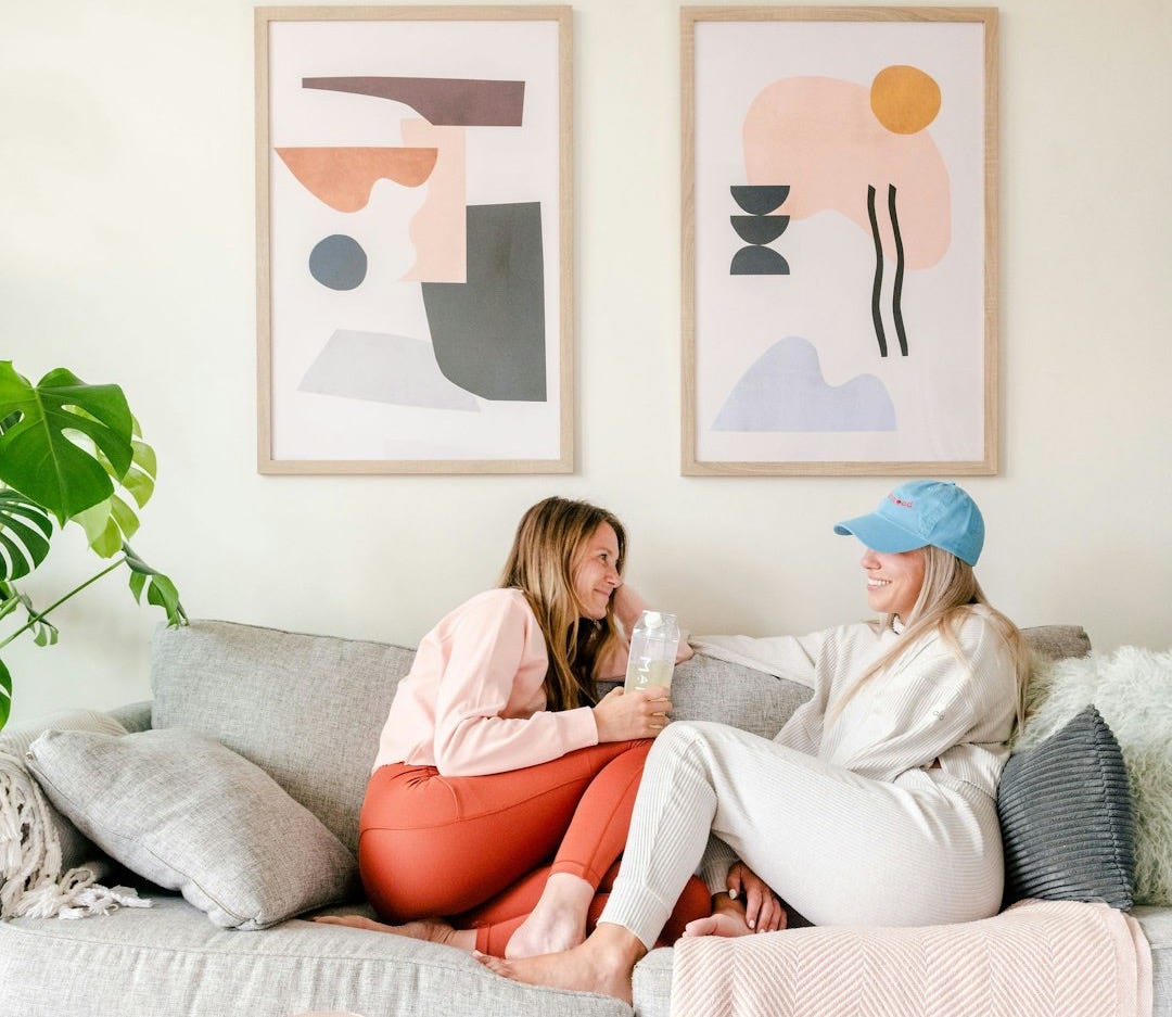 two women sitting on a couch in a living room