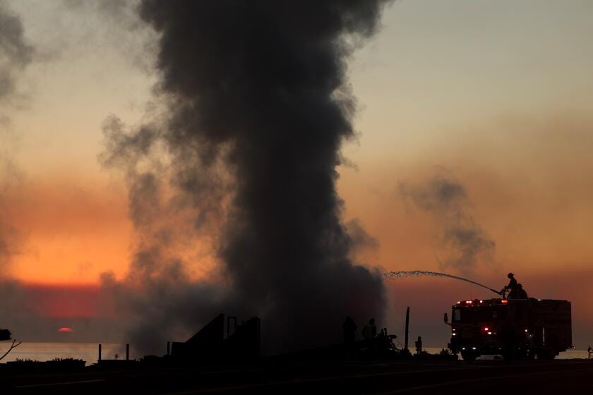 Firefighters put water on a burned down house that was still smoldering from the Palisades fire on PCH in Malibu. 