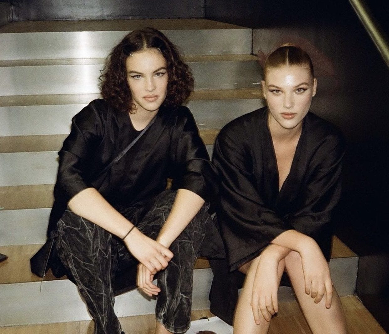 Models Maja Sieroń and Maja Zimnoch sitting on the stairs, backstage at Dolce & Gabbana.